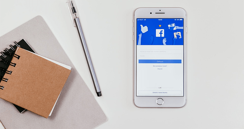 note books, pen and smart phone showing Facebook login page